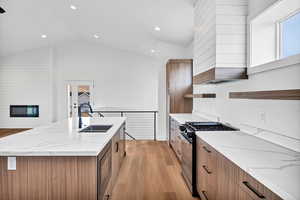 Kitchen featuring brown cabinets, open shelves, light stone counters, light wood-style floors, and recessed lighting