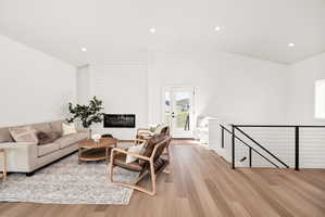 Living area featuring light wood finished floors, recessed lighting, a fireplace, and lofted ceiling
