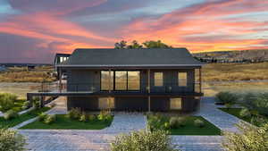 Rear view of house featuring roof with shingles, board and batten siding, a balcony, and a lawn/ landscape in this photo is virtual