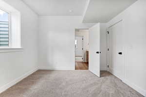Unfurnished bedroom with light colored carpet and baseboards