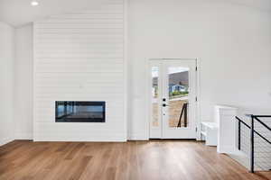 Entryway featuring a fireplace, wood finished floors, high vaulted ceiling, and recessed lighting