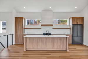 Kitchen with open shelves, freestanding refrigerator, recessed lighting, light stone countertops, and light wood-style flooring