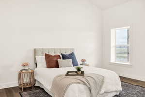 Bedroom featuring dark wood-style floors and baseboards