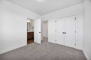 Unfurnished bedroom with carpet, ensuite bathroom, and a closet