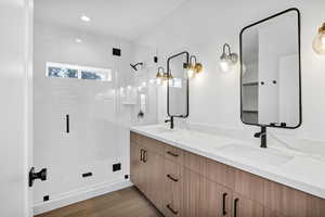 Bathroom with double vanity, a stall shower, dark wood-type flooring, and recessed lighting