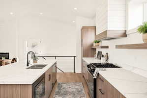 Kitchen featuring dual tone cabinets, modern cabinets, black appliances, light stone countertops, and open shelves