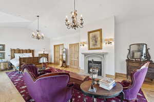 Living room with a chandelier, lofted ceiling, wood finished floors, and a fireplace with flush hearth