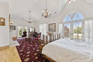 Bedroom featuring a chandelier, access to outside, wood-type flooring, french doors, and lofted ceiling