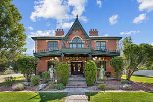View of front of house featuring brick siding, a front lawn, a chimney, french doors, and a porch
