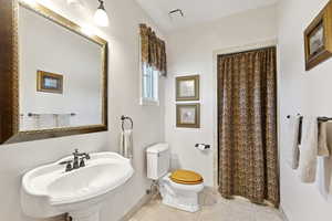 Full bathroom featuring a shower with shower curtain and tile patterned flooring
