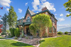 View of front of house featuring a front yard, brick siding, covered porch, a chimney, and a mountain view