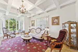 Living room with coffered ceiling, a chandelier, wood finished floors, and beam ceiling