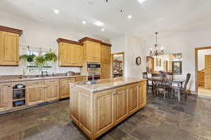 Kitchen featuring a chandelier, appliances with stainless steel finishes, light brown cabinetry, light stone countertops, and recessed lighting