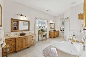 Full bathroom featuring a footed tub, two vanities, and tile patterned flooring