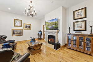 Living room with wood-type flooring, a glass covered fireplace, a chandelier, and recessed lighting