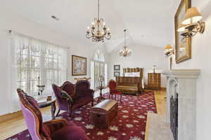 Living room with a chandelier, vaulted ceiling, and wood finished floors