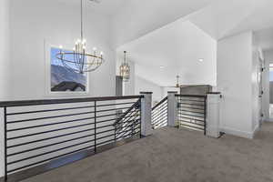 Hall featuring an upstairs landing, carpet, vaulted ceiling, a chandelier, and recessed lighting
