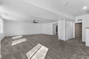 Basement featuring dark colored carpet, a ceiling fan, and recessed lighting