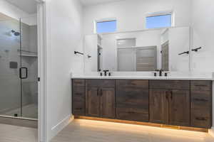Bathroom with a shower stall, double vanity, and light tile patterned floors
