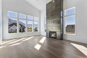 Unfurnished living room with a mountain view, high vaulted ceiling, wood finished floors, a large fireplace, and recessed lighting