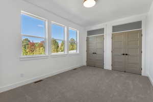 Unfurnished bedroom featuring multiple closets and carpet