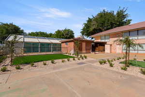 Rear view of house featuring a lawn, a chimney, and a tile roof