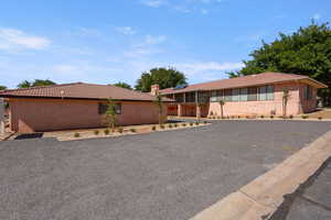 Single story home with a tile roof, solar panels, a chimney, and stucco siding
