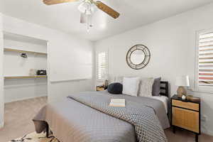 Bedroom with carpet, a spacious closet, and ceiling fan