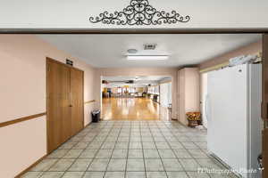 Hallway featuring light tile patterned floors and a textured ceiling