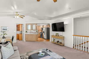Living area featuring light colored carpet, ceiling fan, and vaulted ceiling