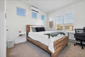Bedroom with carpet flooring, a wall unit AC, and a desk