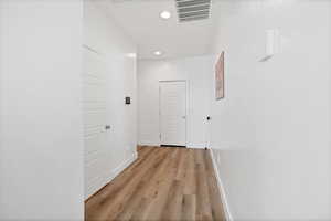 Corridor featuring light wood finished floors and recessed lighting