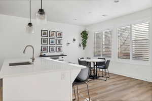 Kitchen featuring pendant lighting, a kitchen breakfast bar, light wood-type flooring, light stone countertops, and recessed lighting