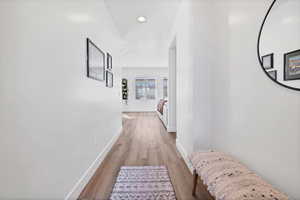 Hallway with light wood-style floors and recessed lighting