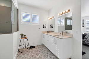 Ensuite bathroom featuring double vanity, plenty of natural light, and walk in shower