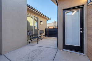 View of exterior entry featuring stucco siding and a patio
