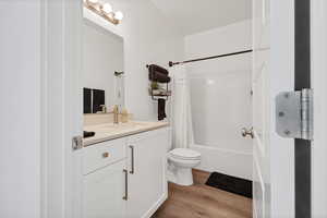 Bathroom with shower / tub combo, vanity, and light wood-style floors