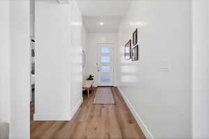 Doorway to outside with wood finished floors and recessed lighting