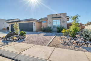 View of front of house with stucco siding, an attached garage, and driveway