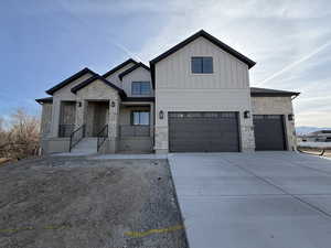 View of front of house featuring stone siding, driveway, and board and batten siding