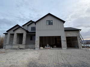 View of front of property featuring stone siding, driveway, and board and batten siding