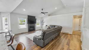 Living area featuring lofted ceiling, light wood finished floors, a fireplace, ceiling fan, and recessed lighting