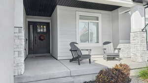 Doorway to property with stone siding and covered porch
