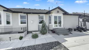 View of front of property featuring stucco siding, roof with shingles, and entry steps