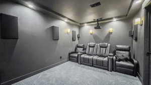 Carpeted cinema room featuring electric panel, recessed lighting, and a tray ceiling