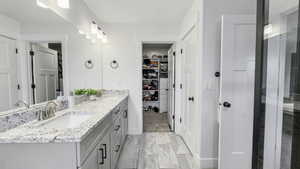 Bathroom with a walk in closet, double vanity, and a shower with door