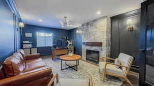 Living room with wood finished floors, a fireplace, a desk, a chandelier, and ornamental molding