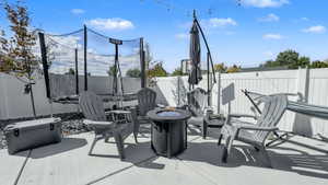 Fenced backyard featuring an outdoor fire pit, a trampoline, and a patio area