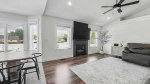 Living area featuring recessed lighting, lofted ceiling, a large fireplace, dark wood-type flooring, and ceiling fan