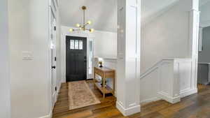 Foyer entrance featuring wood finished floors, a chandelier, and lofted ceiling